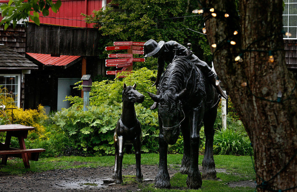 A whimsical sculpture of a western scene centers one of several cozy courtyards found between the shop buildings in Bothell’s Country Village. (Dan Bates / The Herald)
