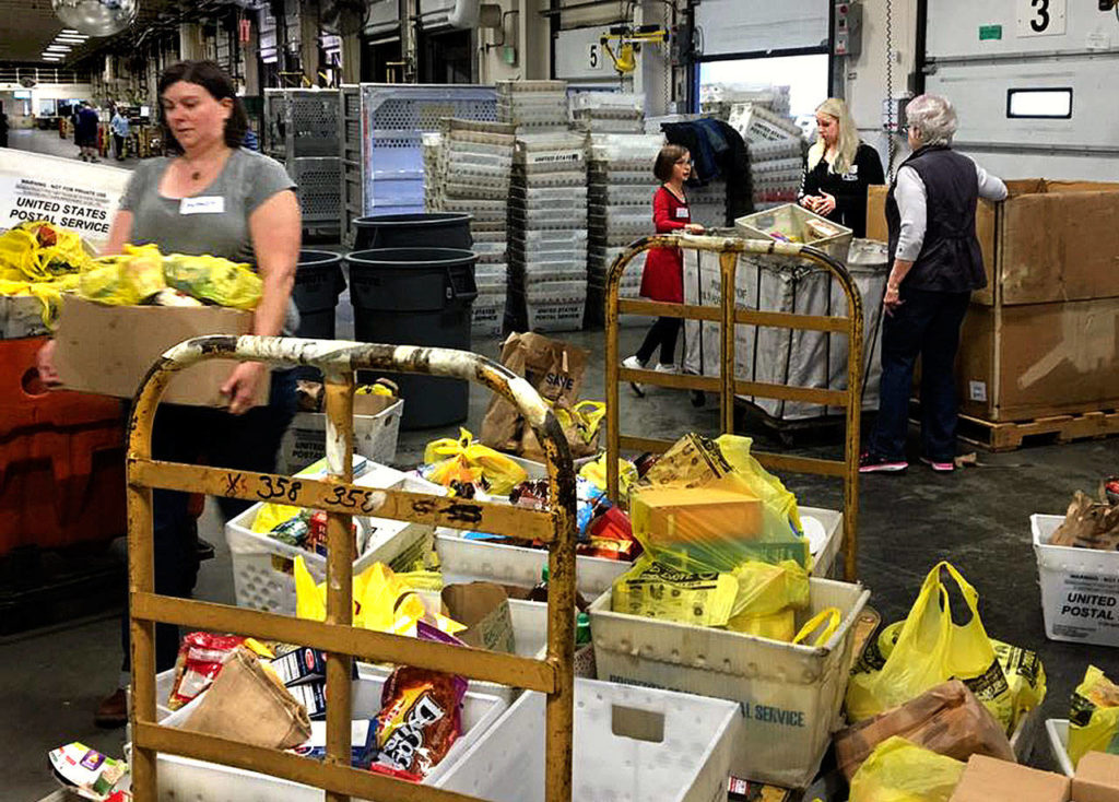 Volunteers unload bags of nonperishable food donated during the 2016 Letter Carriers Food Drive. Scheduled for May 13, the effort to help local food banks feed hungry people in Snohomish County will mark its 25th anniversary this year. (Volunteers of America Western Washington photo)
