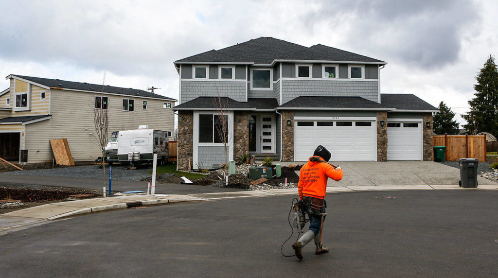 A construction worker walks by houses under construction in a cul-de-sac on 8th Pl SEon Wednesday, March 8, 2017 in Lake Stevens, Wa. (Ian Terry / The Herald)
