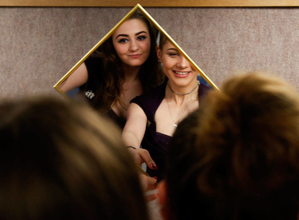 IzSabella Haviland (left) and Tetyana Popach, both 17, try on prom dresses together and share a small mirror Thursday morning, the day before Crossroads High School’s first-ever prom night. (Dan Bates / The Herald)

