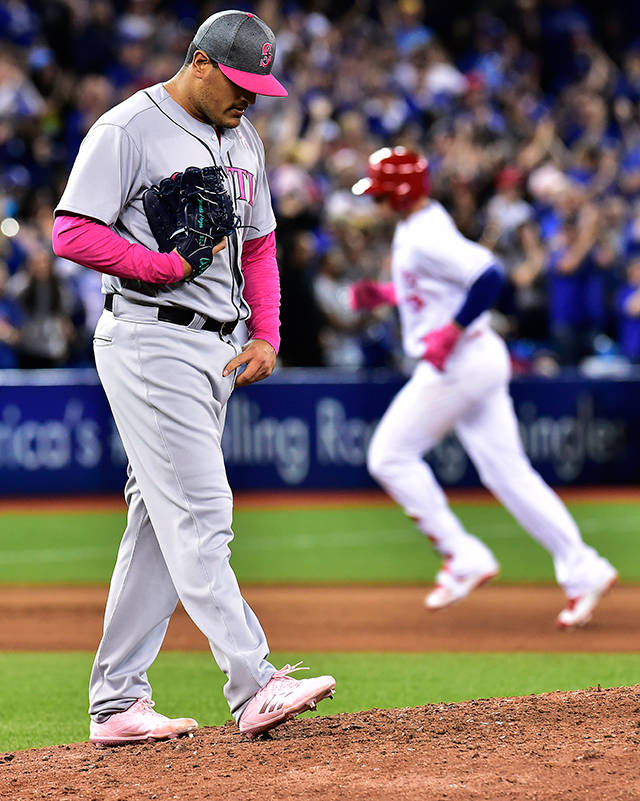 Seattle Mariners relief pitcher James Pazos, left, reacts on the mound after giving up a two-run home run to Toronto Blue Jays’ Justin Smoak, right, who rounds the bases during sixth-inning baseball game action in Toronto, Sunday, May 14, 2017. (Frank Gunn/The Canadian Press via AP)