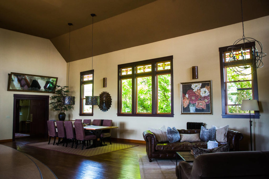The living area of the former Mukilteo Presbyterian Church features a dining table, sitting area and the original windows. (Daniella Beccaria / For The Herald)
