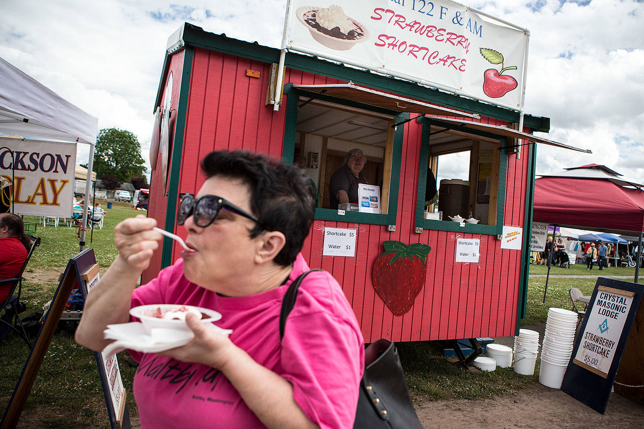 Anita Hills, of Mount Vernon, takes a bite of strawberry shortcake from Crystal Masonic Lodge’s booth at the Marysville Strawberry Festival on June 16. (Ian Terry / The Herald)