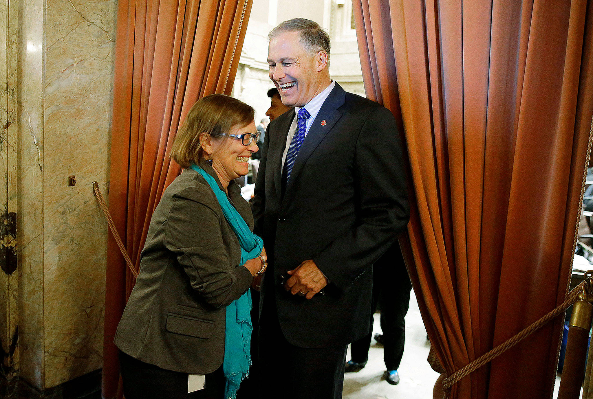 Washington Gov. Jay Inslee (right) greets Rep. June Robinson, D-Everett, in the wings of the House chamber at the Capitol in Olympia after the Legislature approved a new two-year state operating budget. (AP Photo/Ted S. Warren)