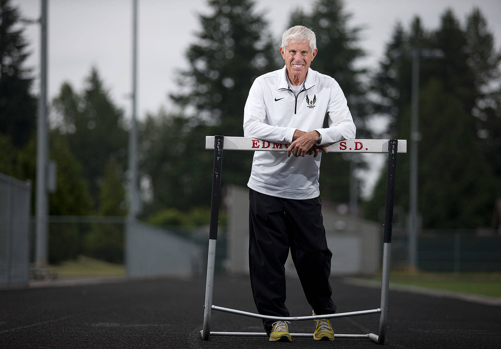 Duane Lewis poses on the Lynnwood High School track Monday. Lewis has retired after 45 years as the Royals’ head track and field coach. (Andy Bronson / The Herald)