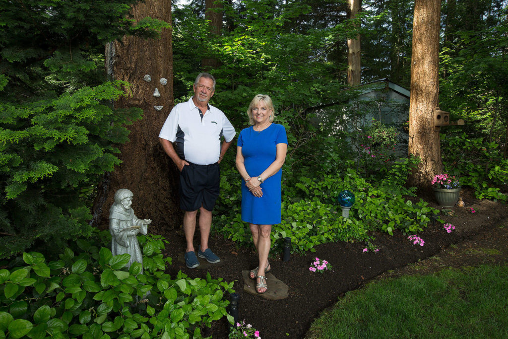 Bill and Carol Arkell stand along their manicured lawn and trees at their home, which will be featured in the Mill Creek Garden Tour. (Andy Bronson / The Herald)
