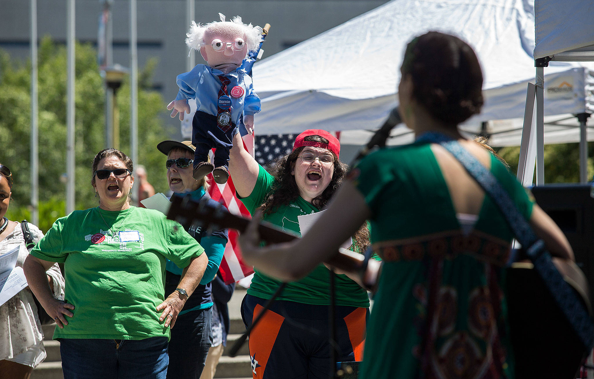 Holding a Bernie Sanders puppet, Leslie Zukor cheers as she and others sing along to the song “Take It Personally” sung by Tae Phoenix at an event called Stop Trumpcare Day at the Snohomish County Courthouse on Thursday in Everett. The protest was organized by Indivisible, an organization of some 6,000 community groups nationally. (Andy Bronson / The Herald)