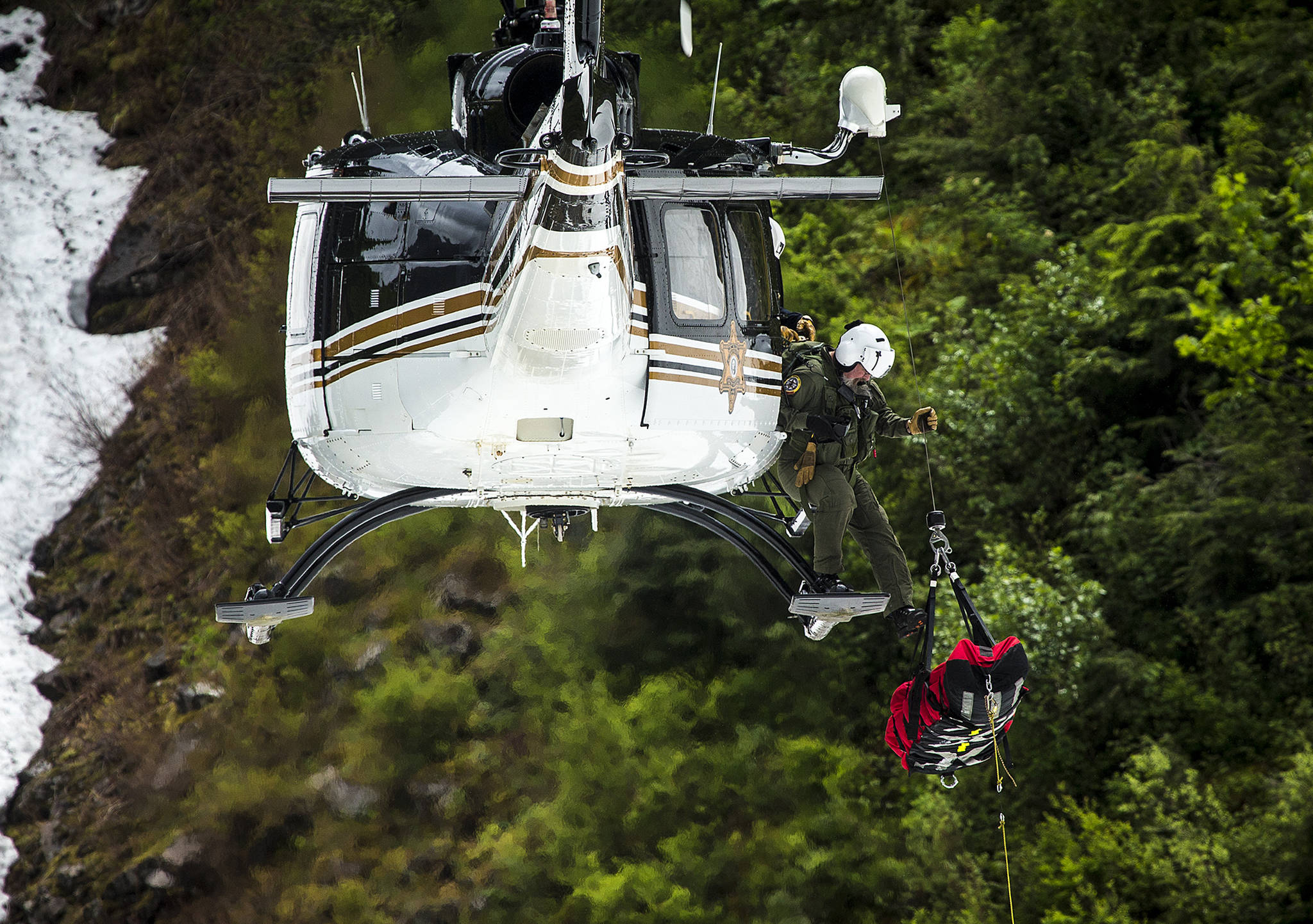 A mock victim is hoisted into a helicopter during Snohomish County Search & Rescue training at the Big Four Ice Caves on Saturday. A spate of rescues on nearby Mount Pilchuck have authorities urging hikers to exercise caution as higher elevation trails can be deceptively difficult to navigate in spring conditions. (Ian Terry / The Herald)