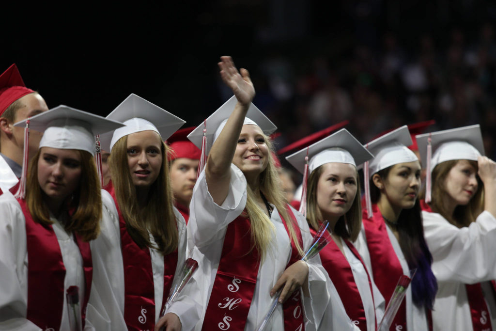 Snohomish High’s Mayah Chisa waves to family as she and classmates get seated for their graduation ceremony at Xfinity Arena on Monday in Everett. (Andy Bronson / The Herald)
