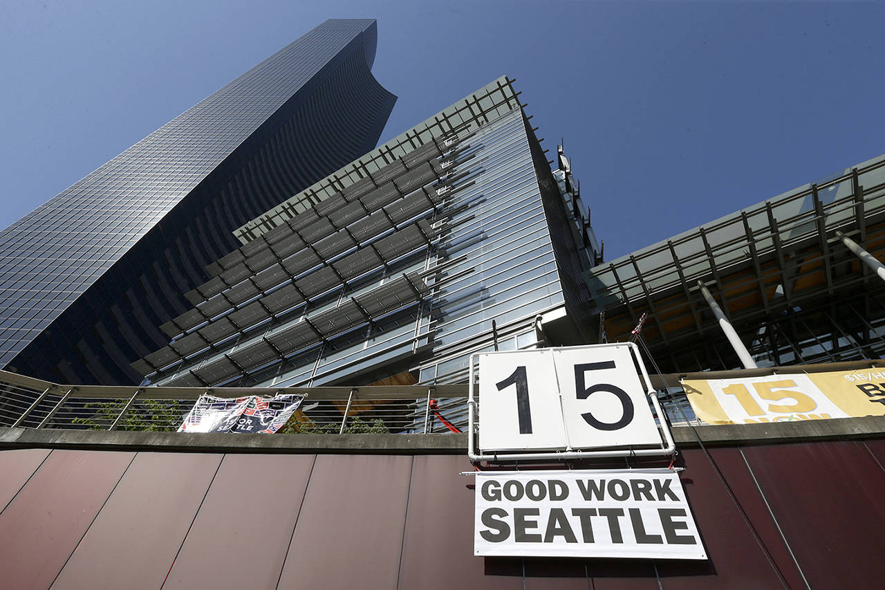 In this 2014 photo, a sign that reads “15 Good Work Seattle” is displayed below Seattle City Hall (right) and the Columbia Center building (left) after the Seattle City Council passed a $15 minimum wage measure. (AP Photo/Ted S. Warren, File)