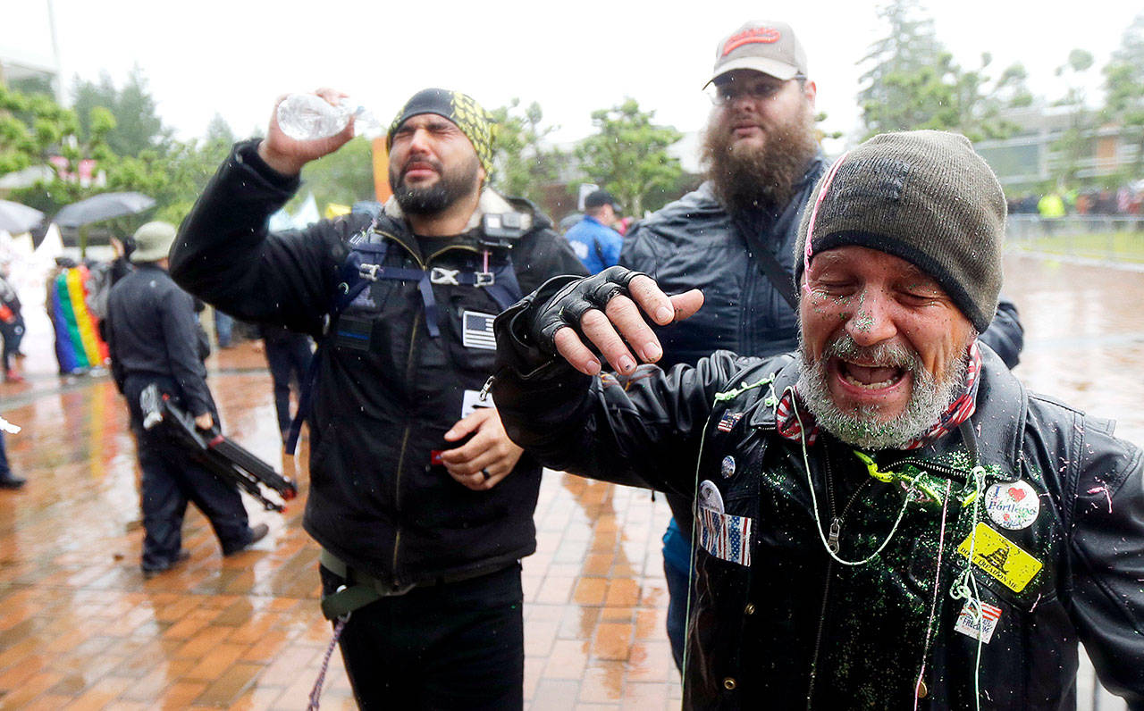 Two men protesting with the conservative group Patriot Prayer react after they said they were sprayed with pepper spray and doused with glitter by counter-protesters Thursday at The Evergreen State College in Olympia. (AP Photo/Ted S. Warren)