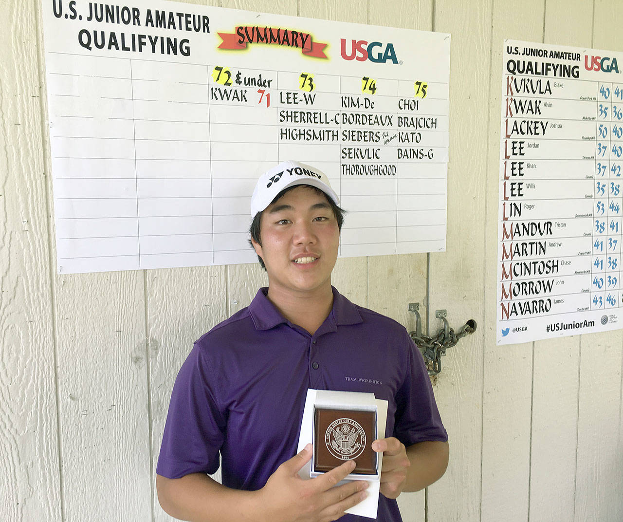 Alvin Kwak poses next to the leader board after winning the U.S. Junior Open qualifier last week at Classic Golf Club in Spanaway. (Washington State Golf Association)