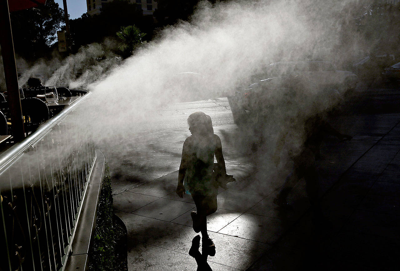 A girl walks through a mister during the start last week of a heat wave in Las Vegas. (AP Photo/John Locher)