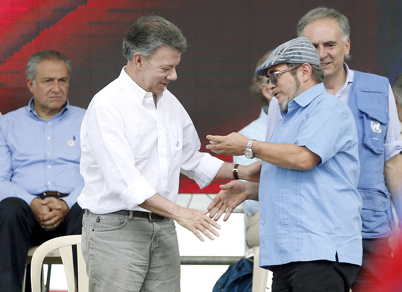 Colombia’s President Juan Manuel Santos (left) shakes hands with Rodrigo Londono, also known as Timochenko or Timoleón Jiménez (right), the top commander of the Revolutionary Armed Forces of Colombia, FARC, during an act to commemorate the completion of the disarmament process in Buenavista, Colombia, on Tuesday, June, 27. (AP Photo/Fernando Vergara)
