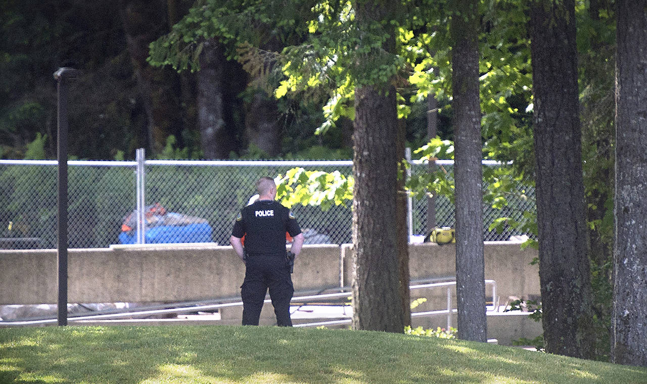 An Evergreen State College police officers keeps watch over campus as student evacuate following a “direct threat” on Thursday, June 1. (Tony Overman /The Olympian via AP)