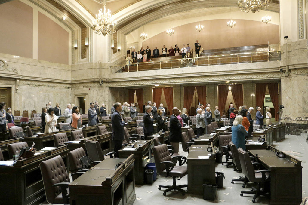 Lawmakers at the House stand during the Pledge of Allegiance on Tuesday in Olympia. The Legislature must send a new two-year budget this week or else risk a partial government shutdown. (Rachel La Corte / Associated Press)

