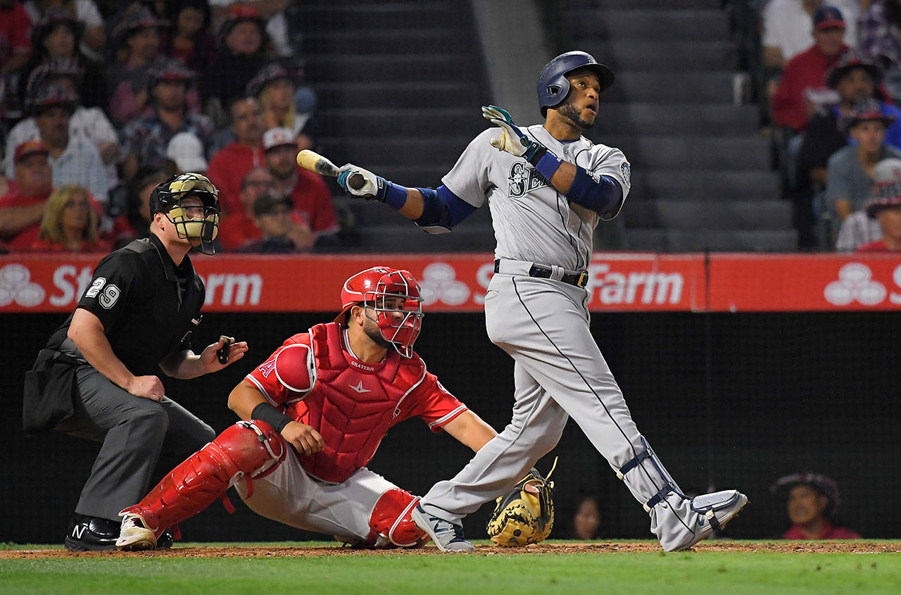 The Mariners’ Robinson Cano (right) hits a three-run home run as Angels catcher Juan Graterol watches along with home plate umpire Sean Barber during the fifth inning of a game June 30, 2017, in Anaheim, Calif. (AP Photo/Mark J. Terrill)