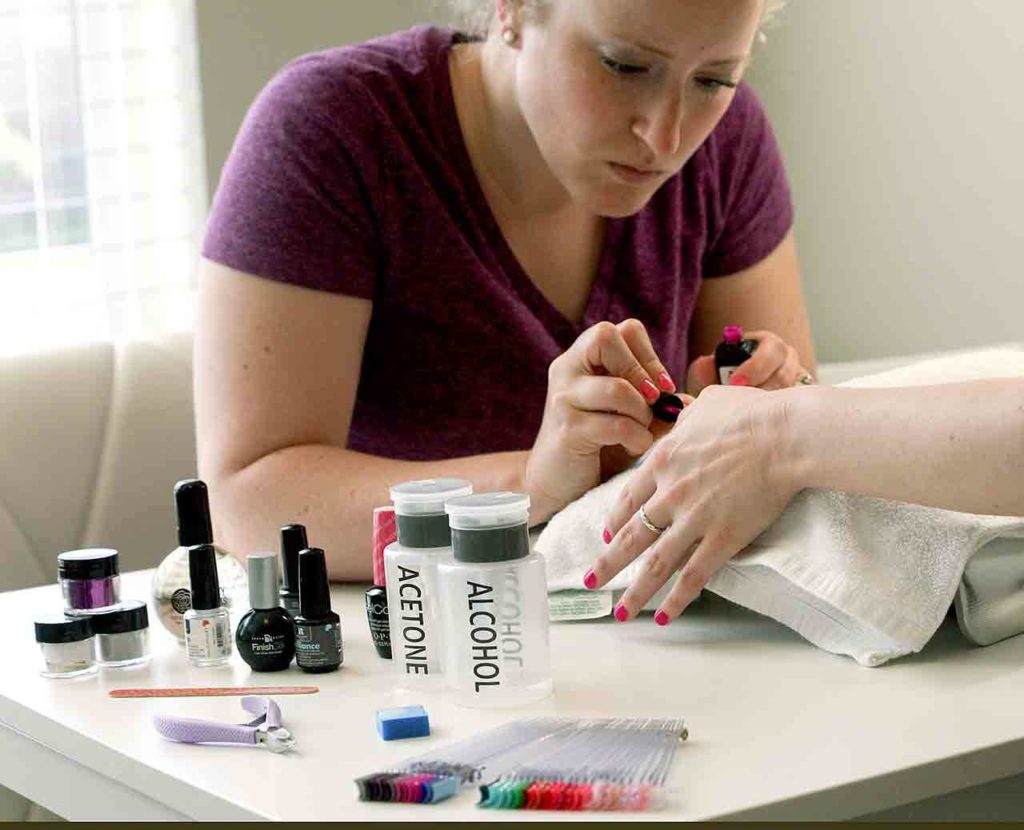 The author applies the second of two coats of gel polish to her sister’s nails. Like traditional nail enamel, gel requires a base coat, two coats of color polish and a top coat. Each layer is applied and cured to a hard gel finish via a LED light. (Vanessa McVay / The Herald)
