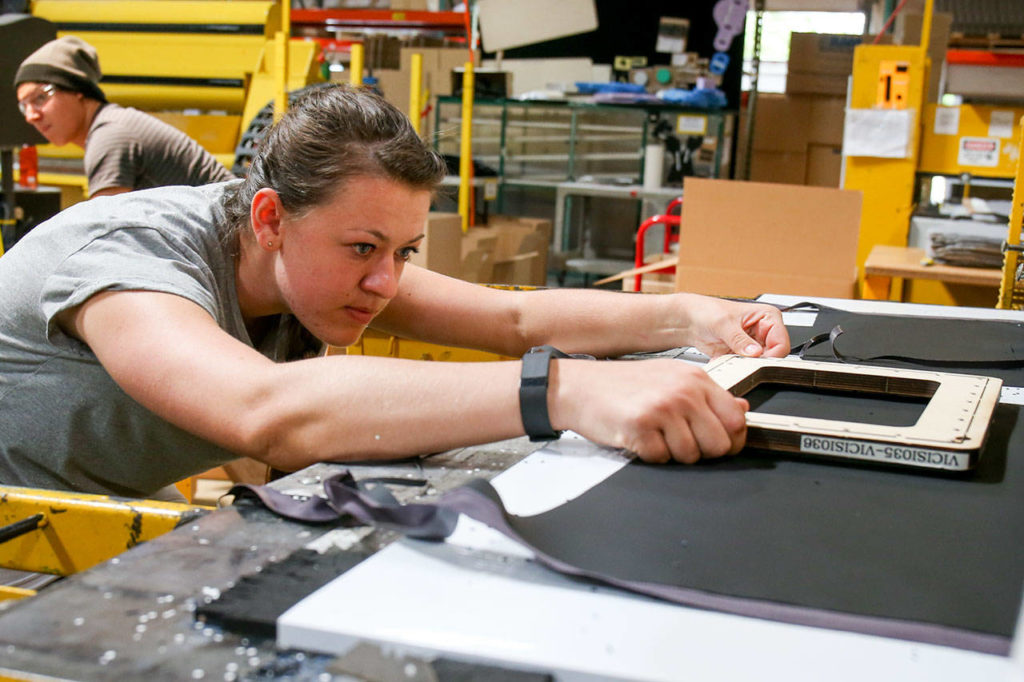 Katie Put uses a die to cut fabric and form at RAM Technologies in Mukilteo on June 7. (Kevin Clark / The Herald)
