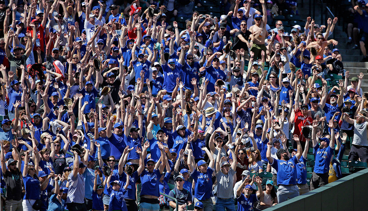 Fans, many wearing Toronto Blue Jays’ blue shirts, stand as a “wave” rolls through the stadium in the seventh inning of a baseball game against the Seattle Mariners, Sunday, June 11, 2017, in Seattle. (AP Photo/Elaine Thompson)