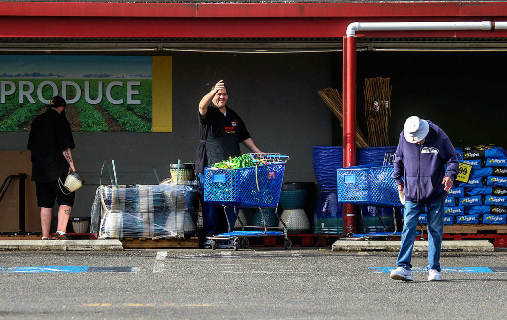 As Williams starts on his morning walk Wednesday, he gets a friendly wave from Tod Jackson, co-owner of Grocery Outlet Bargain Market on Everett Mall Way. (Dan Bates / The Herald)
