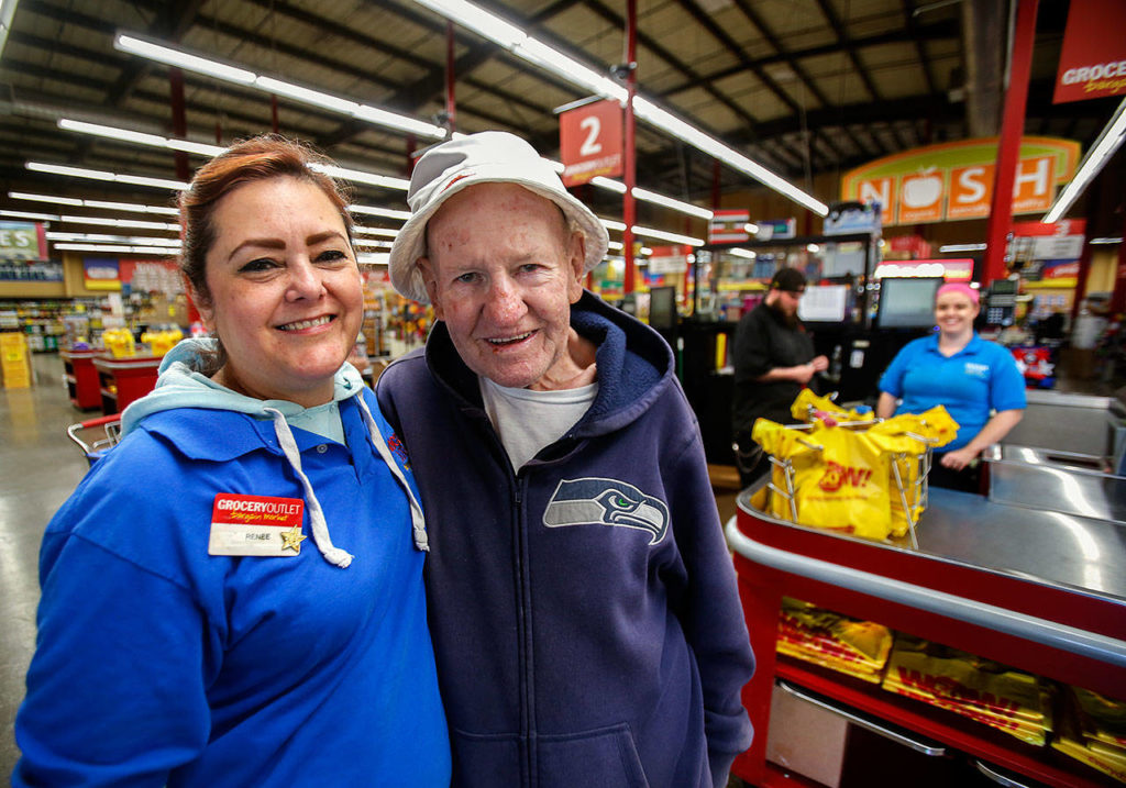Renee Steuer, a checker at Grocery Outlet Bargain Market on Everett Mall Way, hugs Williams, who begins and ends his daily walk at the store. Each day, Williams gives Steuer his copy of The Daily Herald, which he reads at 4:30 a.m. (Dan Bates / The Herald)
