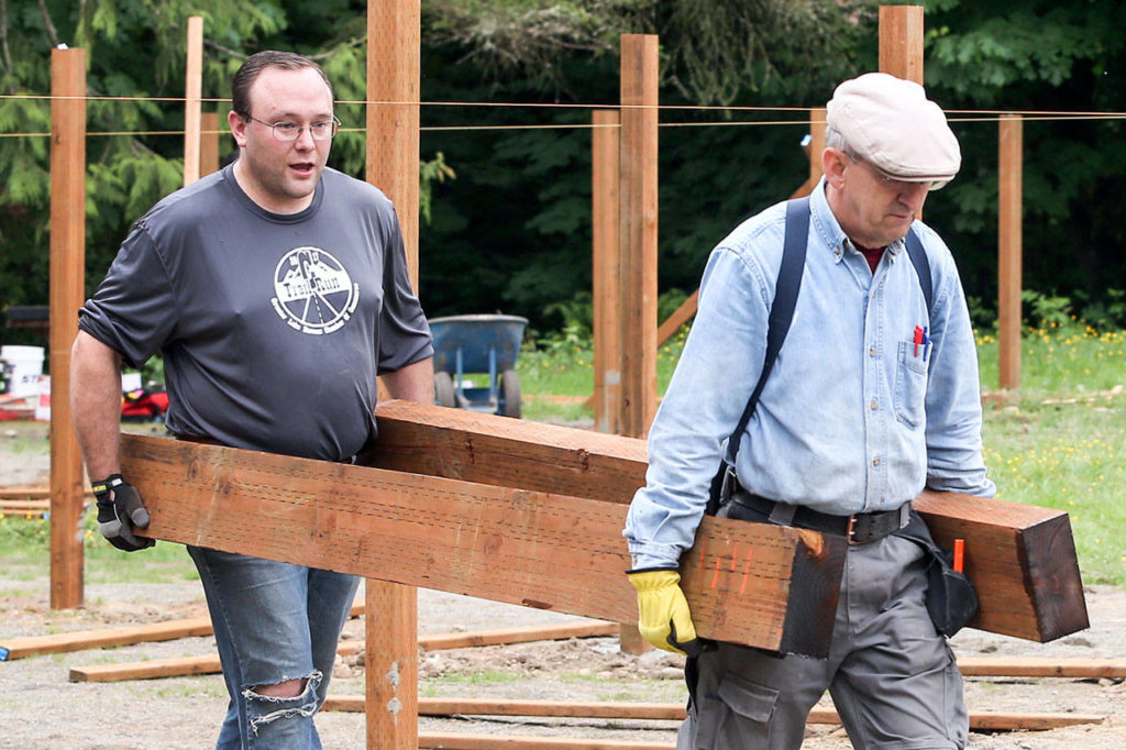 Joel Bockovich and Kim Daughtery haul timbers. (Kevin Clark / The Herald)
