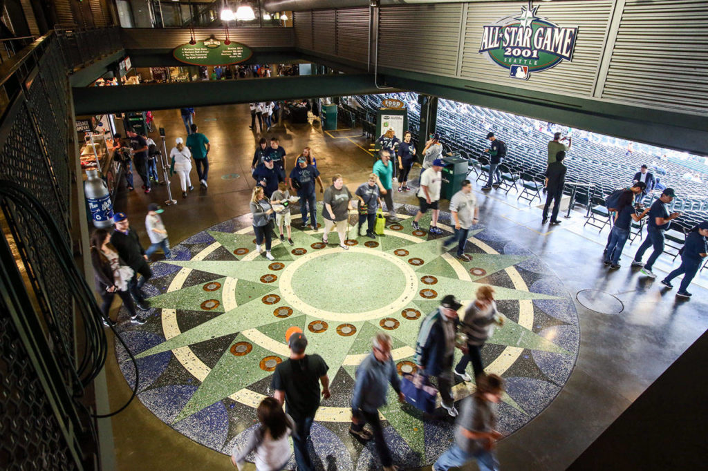 Baseball fans in the main concourse walk over the 27-foot diameter terrazzo compass rose, the icon of sea navigation and keystone of the Mariners logo. (Kevin Clark / The Herald) 
