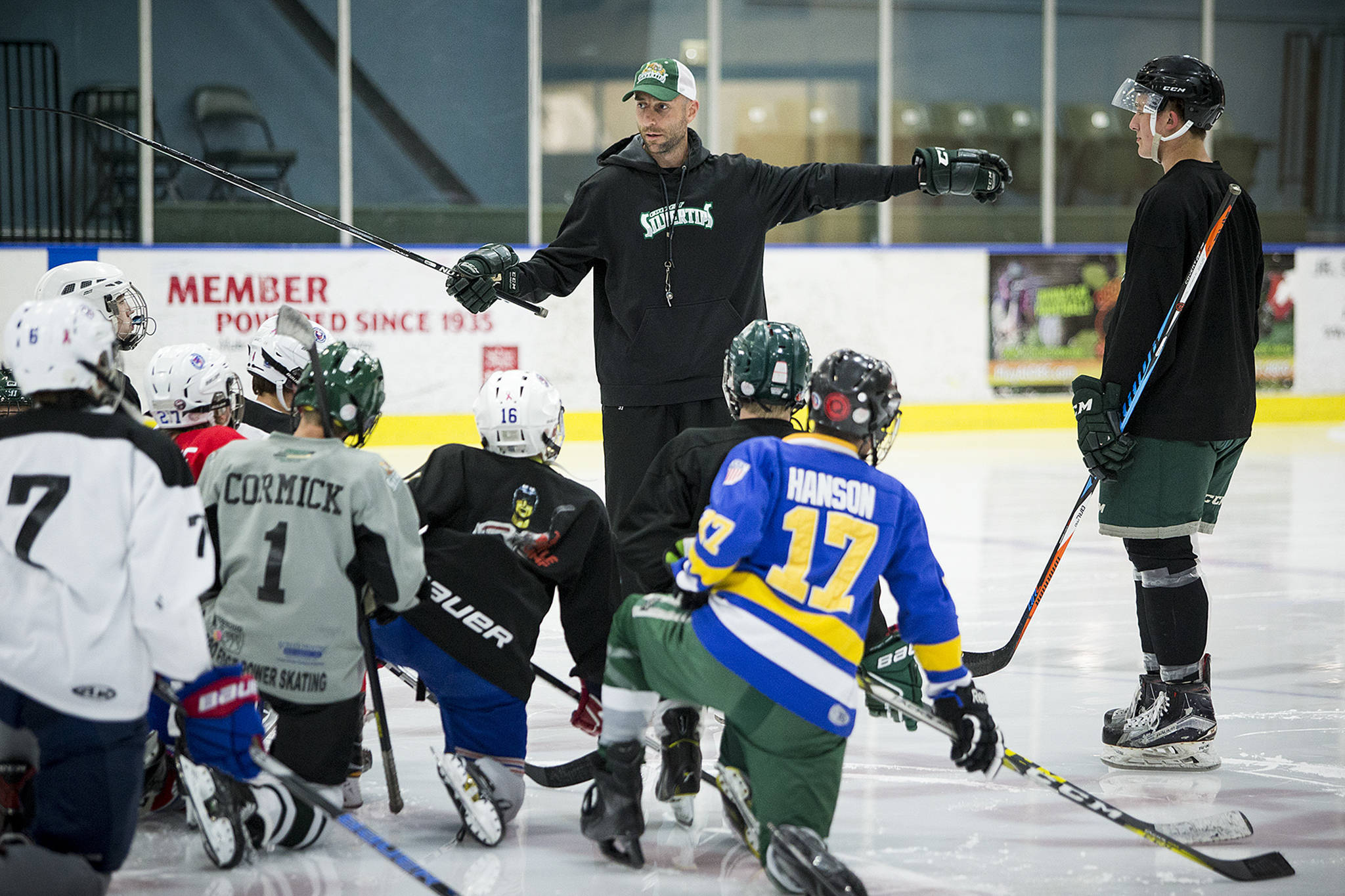 Everett Silvertips assistant coach Mitch Love (center) gives instruction with the help of Silvertips defenseman Wyatte Wylie (right) during a youth hockey camp at the Xfinity Arena Community Ice Rink on May 31. (Ian Terry / The Herald)