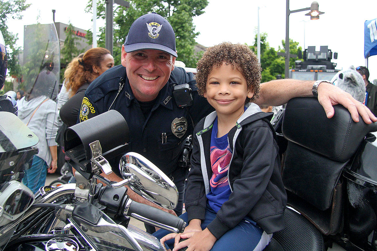 Officer Chuck Freeman with a child at the Lynnwood Police Department’s fourth annual Cops and Kids event. About 1,000 people stopped by the Alderwood mall plaza to meet officers and learn about their jobs. Photo credit: Linda Deppa