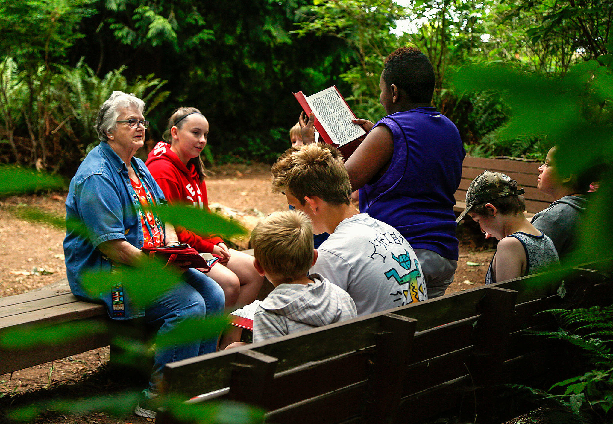 Marillen Bouck, 79, listens intently as Sibusiso Ndhlovu, 10, reads a passage from the Bible during a short study in the chapel at Camp Cascadia on Friday. Although Bouck turns 80 Aug. 5, she is young enough to take over daily duties for her mother, camp founder Esther McChesney, 102. (Dan Bates / The Herald)