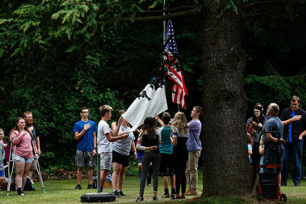 Daily routines at Camp Cascadia begin with raising the flags. (Dan Bates / The Herald)
