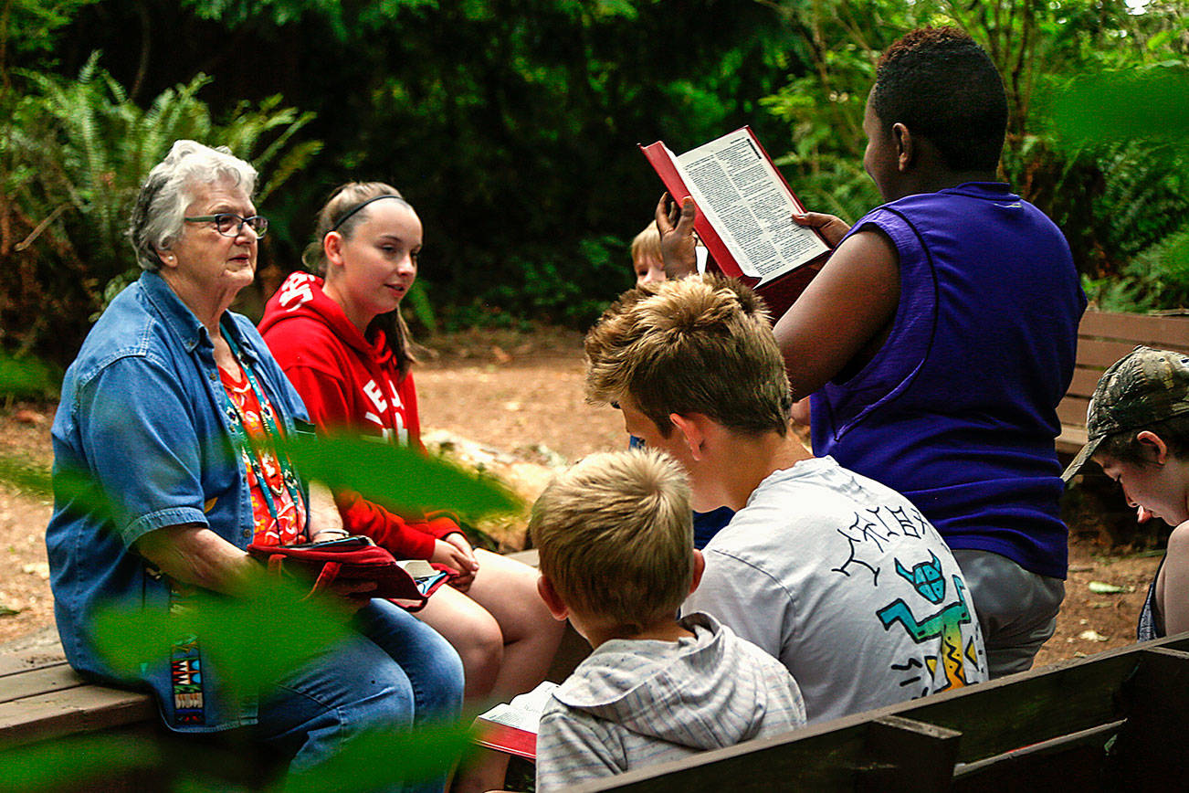 Marillen Bouck, 79, listens intently as Sibusiso Ndhlovu, 10, reads a passage from the Bible during a short study in the woodsy chapel at Camp Cascadia on Friday. Although Bouck turns 80 Aug. 5, she is plenty young enough to take over daily duties for her mother, Esther McChesney, 102, who founded the place 48 years ago so city kids might experience a week at summer camp. (Dan Bates / The Herald)