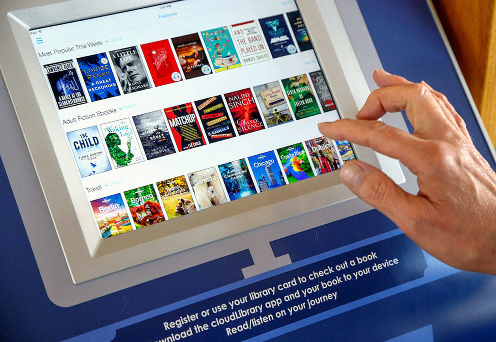 A user browses titles Monday on the Everett Public Library’s ebook kiosk, which was installed recently at Everett Station. Use of the Cloud Library kiosk is free, and those without an Everett library card may sign up for a temporary card to download books. (Dan Bates / The Herald)

