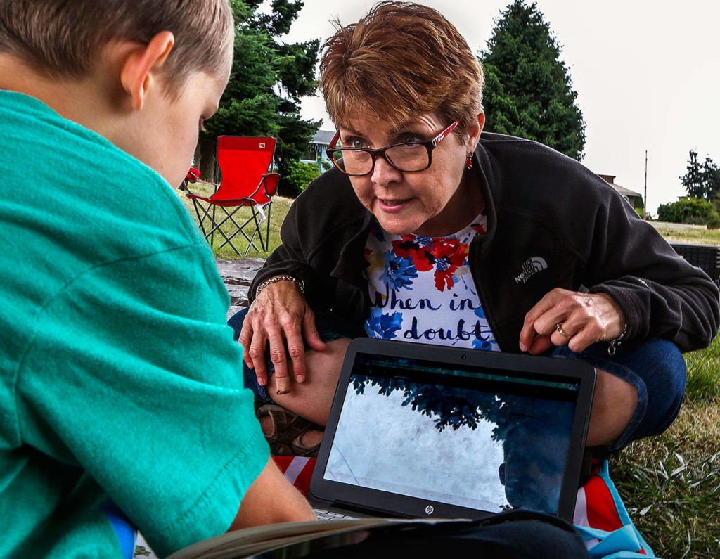 Yob, using a laptop with Accelerated Reader Test, is able to help Aaden Garner, 7, test his reading comprehension skills after reading a book titled “Fossils.” (Dan Bates / The Herald)
