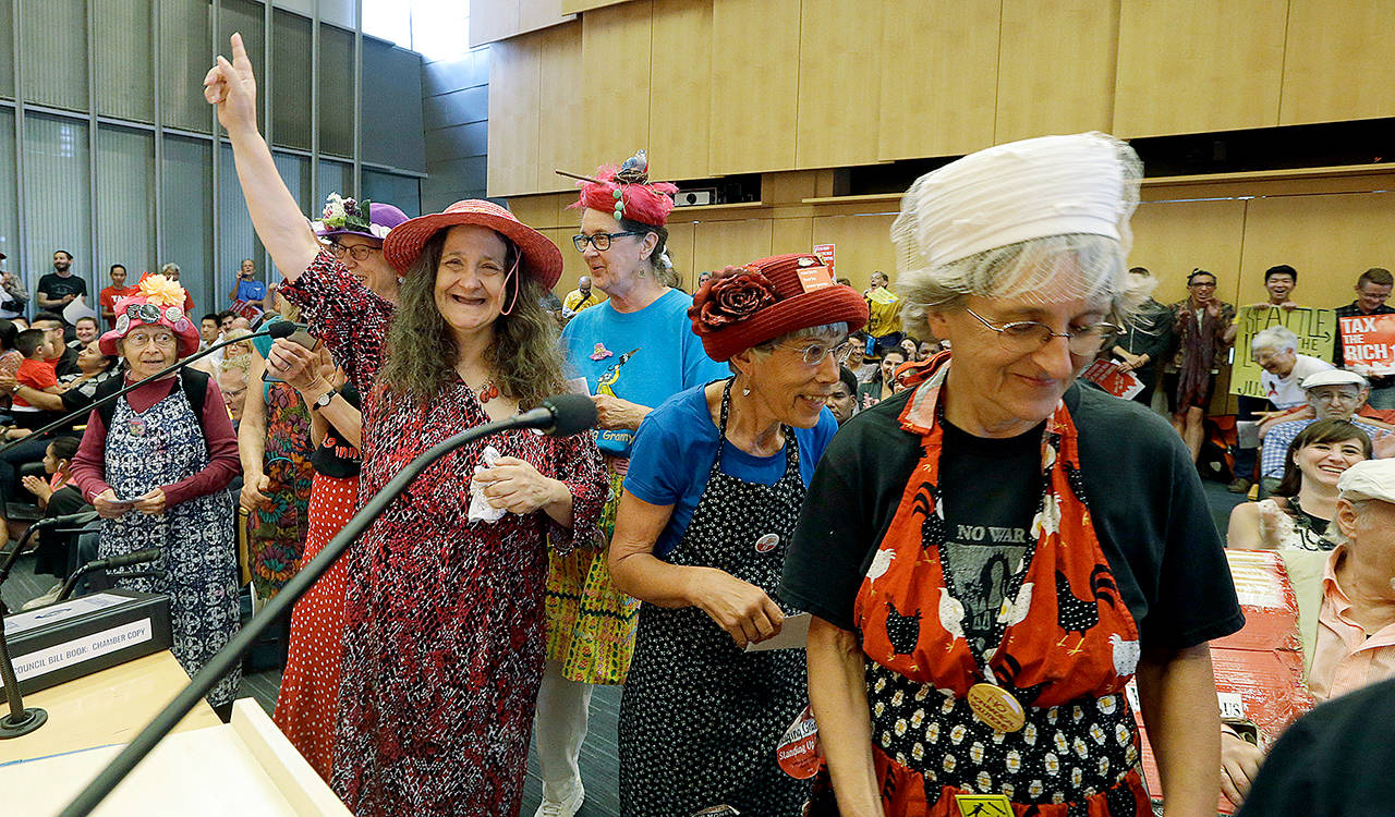 Members of the Seattle Raging Grannies finish their presentation at a Seattle City Council meeting, where a city income tax on the wealthy was being considered on Monday. The women sang a song in support of the measure, which was approved. (AP Photo/Elaine Thompson)