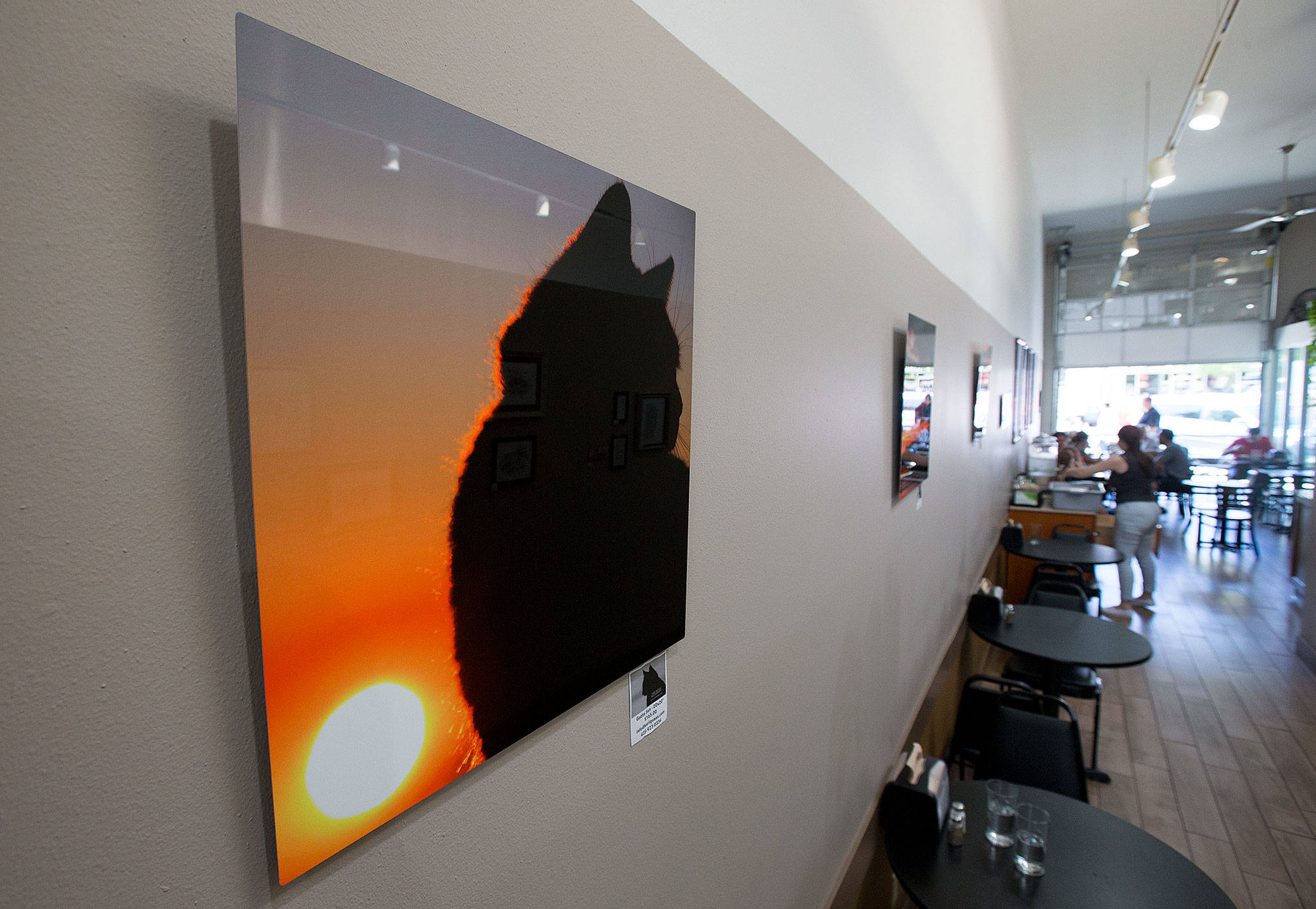One of artist Kari Quaas’ sunset photos hangs at Valley Organic Deli in Everett. The deli is one of 20 business participating in the Everett Art Walk tonight. (Andy Bronson / The Herald)
