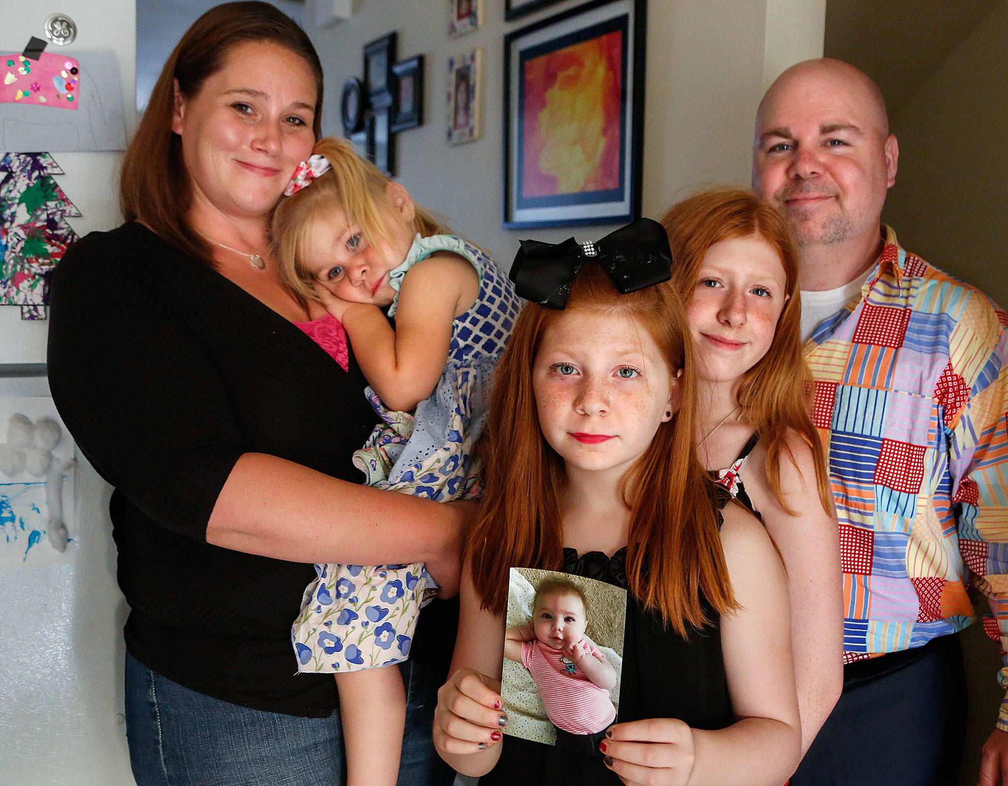 The Nickerson family from left, Olivia, Willow, 3, Ryleigh, 10 (holding photo of Rowan, who died at 7 months), Aubrey, 12, and Joshua. Losing the littlest one to SIDS has been heartbreaking for everyone. But, knowing two other babies are living because of Rowan’s donated heart valves has provided some comfort. (Dan Bates / The Herald)