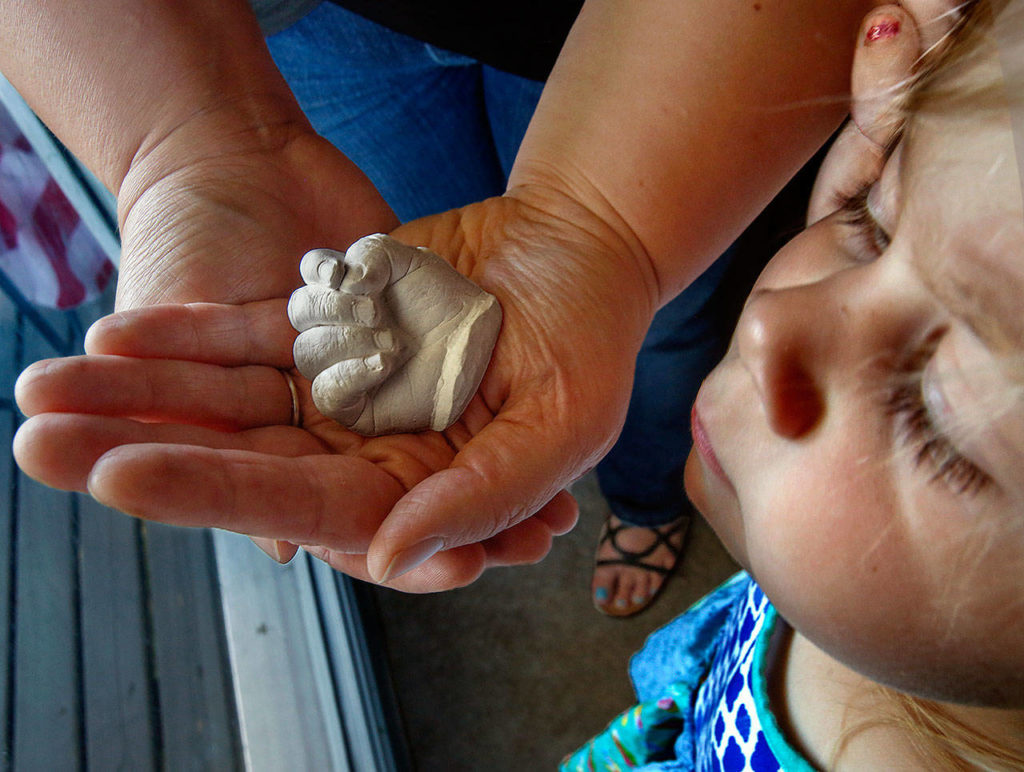 Near the kitchen window, Olivia Nickerson lets her daughter, 3-year-old Willow, look at a plaster casting of baby Rowan’s hand. (Dan Bates / The Herald)
