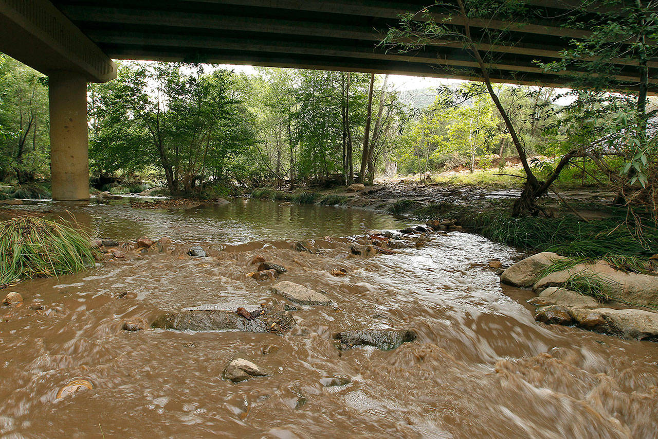 Muddy floodwaters of the East Verde River flow under a bridge where one victim of the flash flood was found during a search and rescue operation by the Gila County Sheriff’s Office on Sunday in Payson, Arizona. (AP Photo/Ralph Freso)