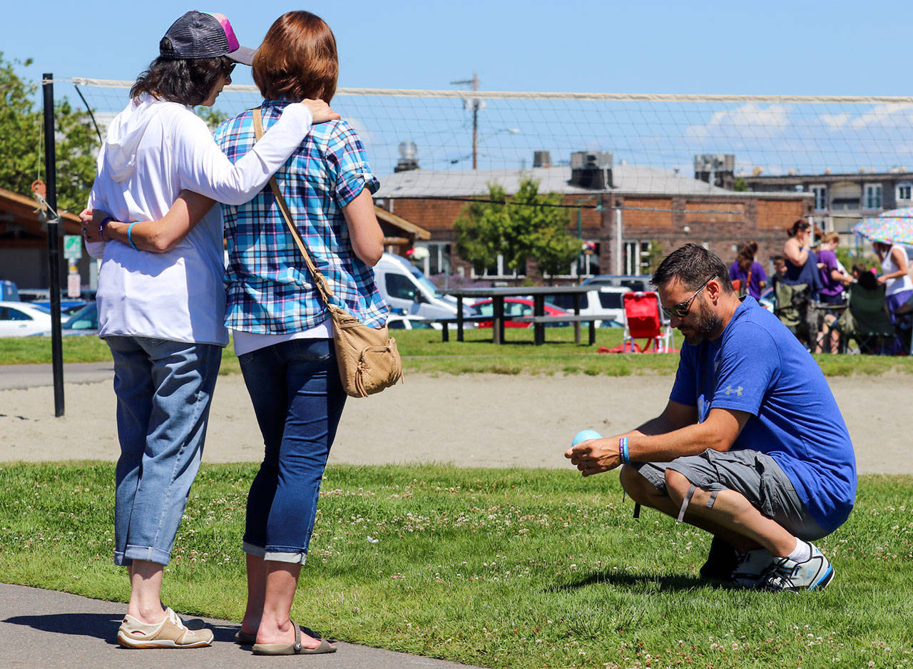 Judi Halverson (left) with her daughter, Nikki Ebner, join Brad Ebner at Lighthouse Park in Mukilteo on Sunday. They were joined by more than 100 people to mark one year after the murder of Jordan Ebner and two others. (Kevin Clark / The Herald)