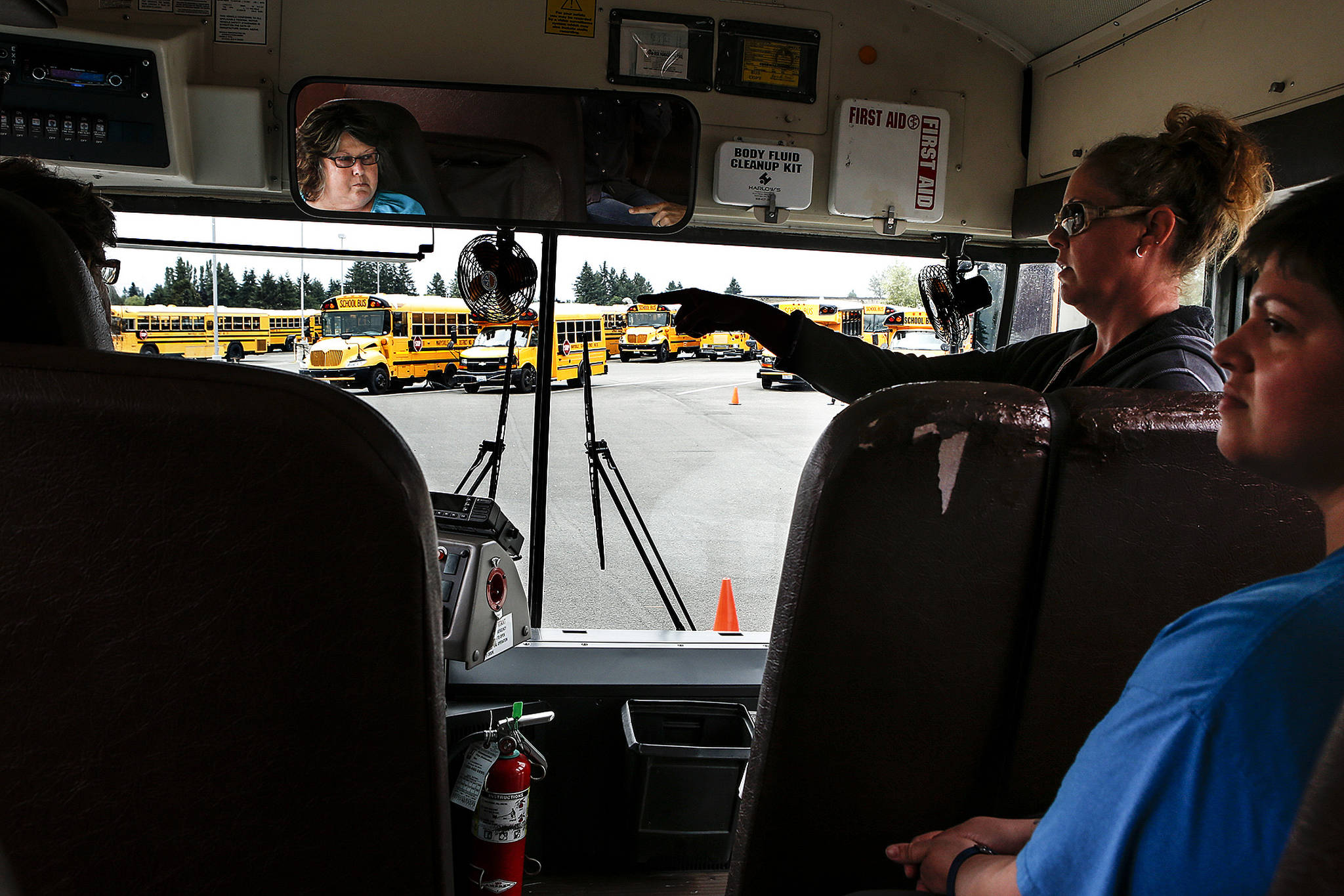 Jenny Lagadinos (center right), a driver and trainer for the Marysville School District, gives instructions to Sue Hubbard (left), of Granite Falls, as fellow trainee Margaret Mitchell (right), of Arlington, looks on while training in Marysville on Thursday, July 27. (Ian Terry / The Herald)
