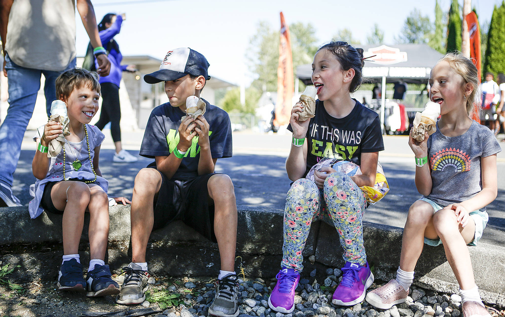 Korbehn Kahm (left), 5, takes a gulp of ice cream as Cedric Sterett (center left), 9, Mya Sterett (center right), 11, and Eevea Kahm, 6, enjoy their own cones during the first day of Aquafest in downtown Lake Stevens on Friday. (Ian Terry / The Herald)