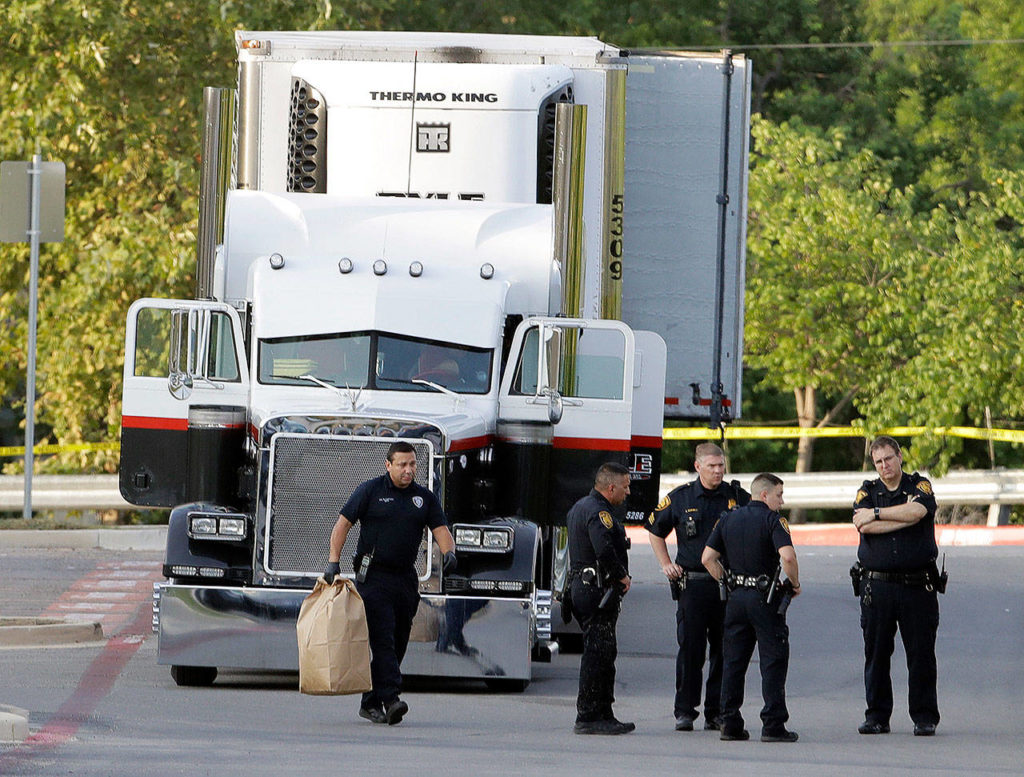 San Antonio police officers investigate the scene on Sunday where eight people were found dead in a tractor-trailer loaded with at least 30 others outside a Walmart store in stifling summer heat. (AP Photo/Eric Gay)
