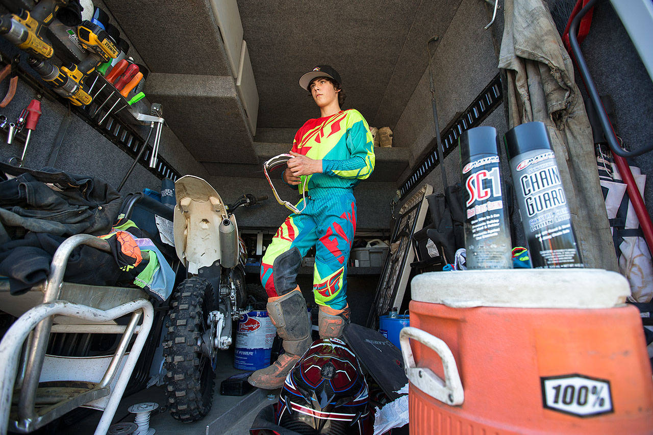 Junior motocross rider Cobey Carper, 14, of Gold Bar applies tear-offs to his goggles before a July 18 practice at Evergreen Speedway in Everett. (Andy Bronson / The Herald)