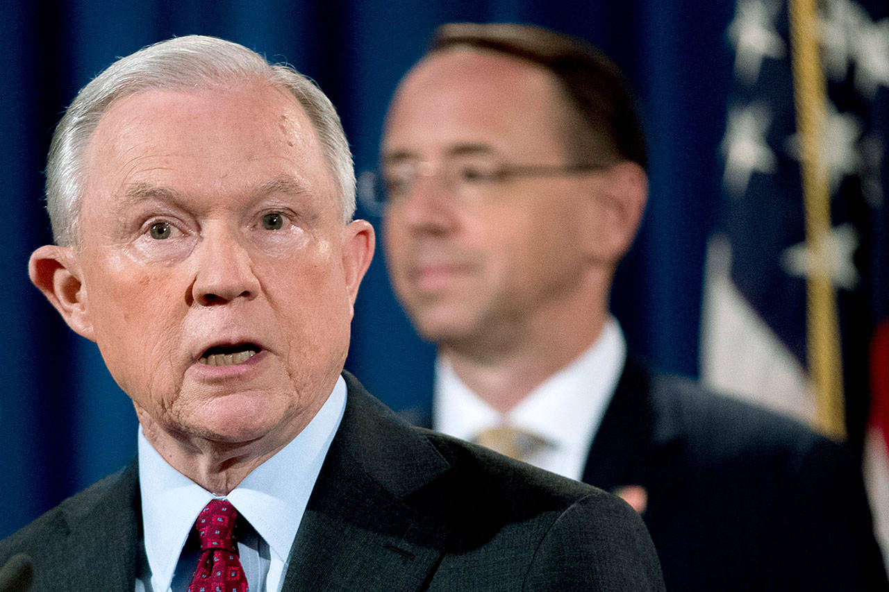 Attorney General Jeff Sessions (left), accompanied by Deputy Attorney General Rod Rosenstein (right), speaks at a news conference to announce an international cybercrime enforcement action at the Department of Justice, on July 20 in Washington. (AP Photo/Andrew Harnik)