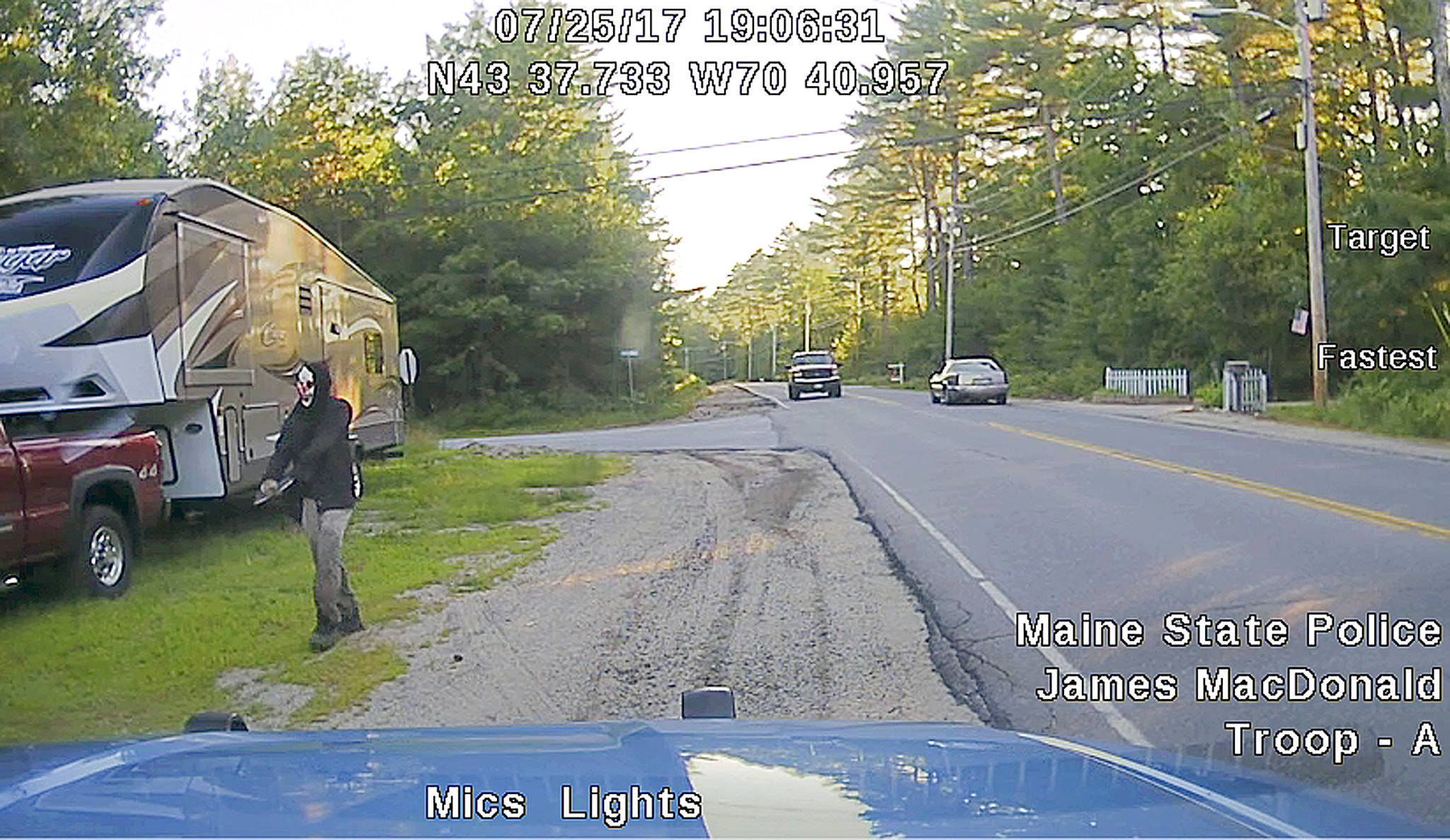 This dashboard camera image released by the Maine State Police shows a man strolling down a street in Hollis, Maine. Police said he was wearing a clown mask with a machete taped to his amputated arm. (Maine State Police via AP)