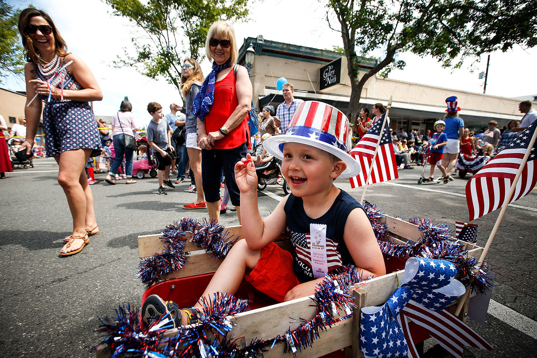 Jackson Emerick, 4, of Shoreline, tosses candy out to crowds lining Main Street in downtown Edmonds during the Edmonds Kind of Fourth Parade on Tuesday. (Ian Terry / The Herald)