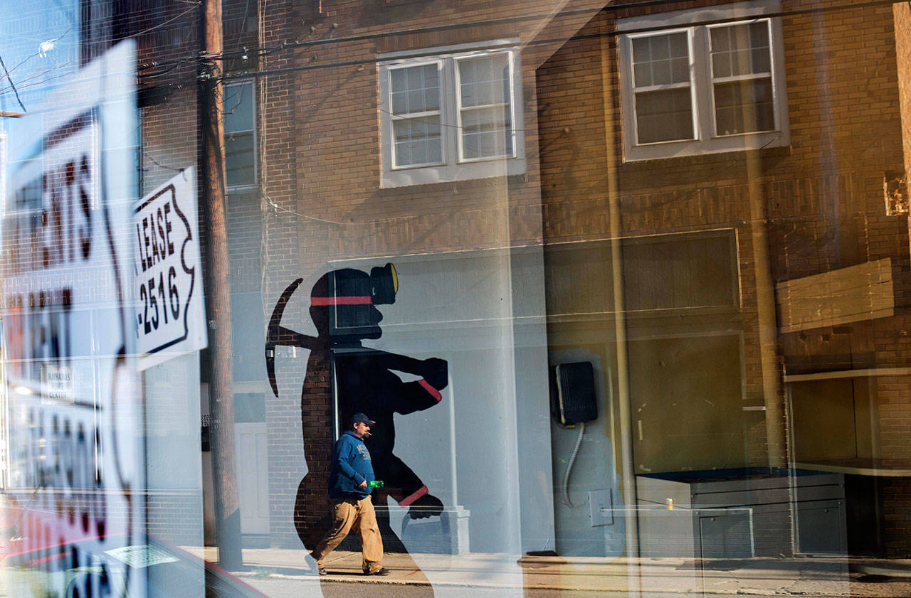 A mural of a coal miner stands in an empty storefront as signs advertising vacant apartments and stores hang in the windows along the main business street in Cumberland, Ky in October, 2014. (David Goldman/Associated Press file photo)