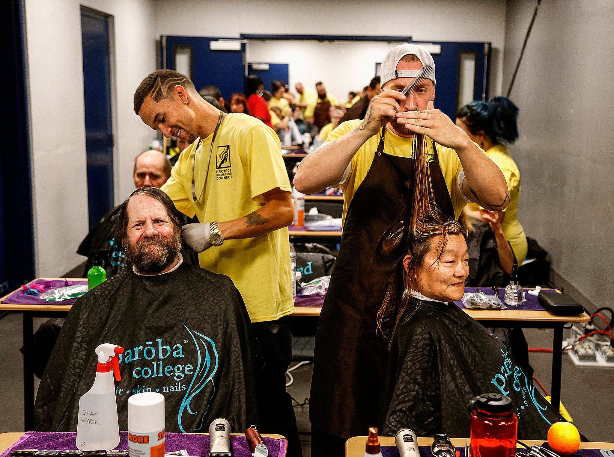 Alex Frazier (left) cuts the hair of Cody Phillips while David Hutton does Lohti Hevly’s hair during last year’s Project Homeless Connect. The two were volunteering from Paroba College of Cosmetology in Everett. This year’s event is scheduled for 9 a.m.-2 p.m. July 20 at Evergreen Middle School in Everett. (Dan Bates/The Herald)